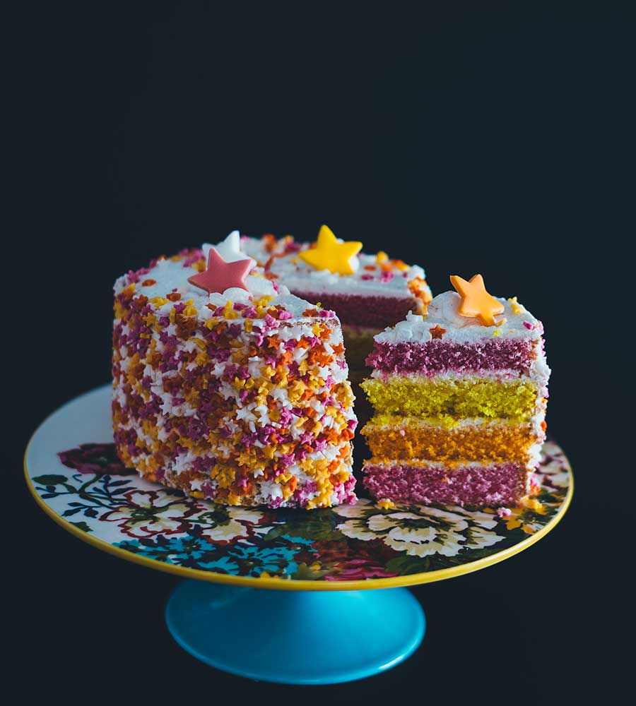 pink, orange, and yellow layered cake with star sprinkles.