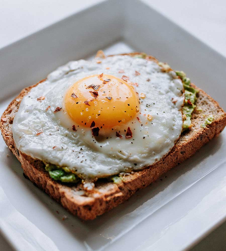 toast with avocado and sunny-side up egg on top.