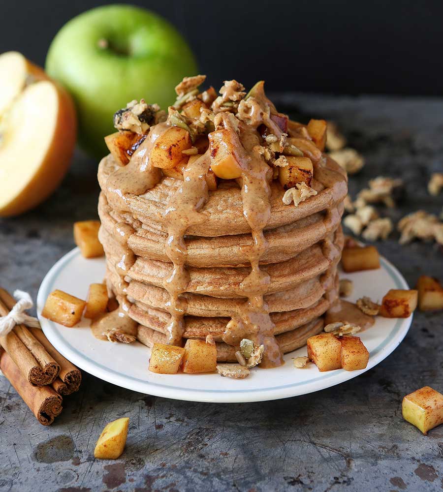 stack of pancakes topped with cinnamon apples and sauce.