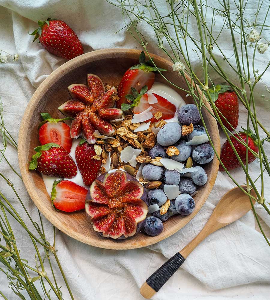 bowl of strawberries, pomegranate, blueberries, and granola.
