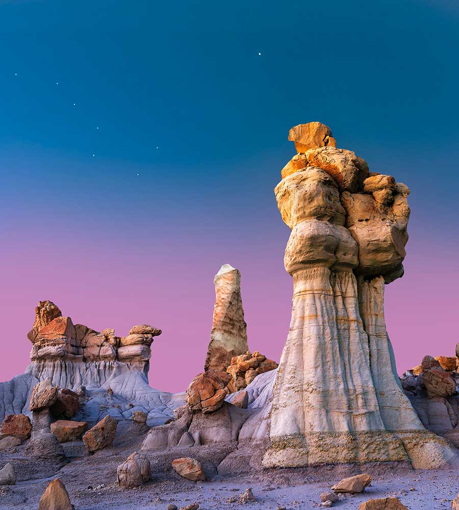 brown and white rock formation against a pink and blue sunset.