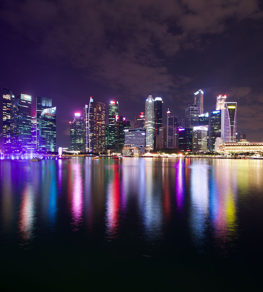 colorful city skyline at night with reflection on the water.