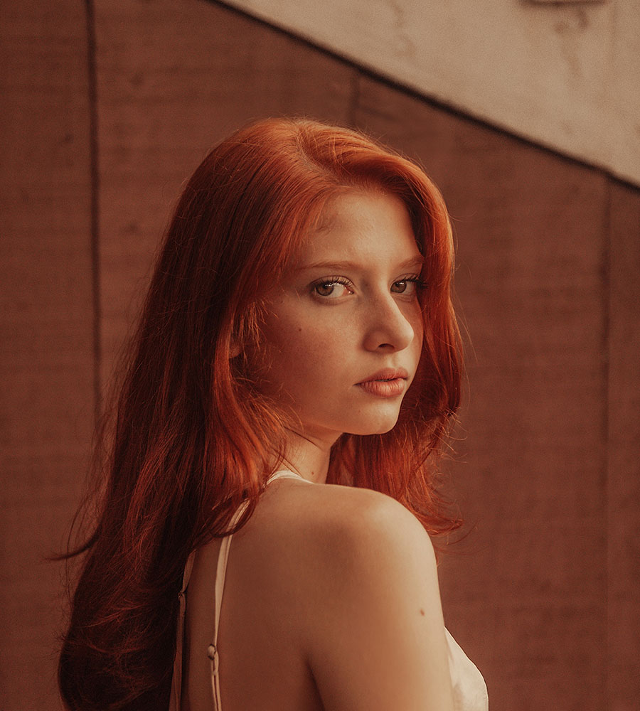 woman with red hair looking over her shoulder with a sultry look.